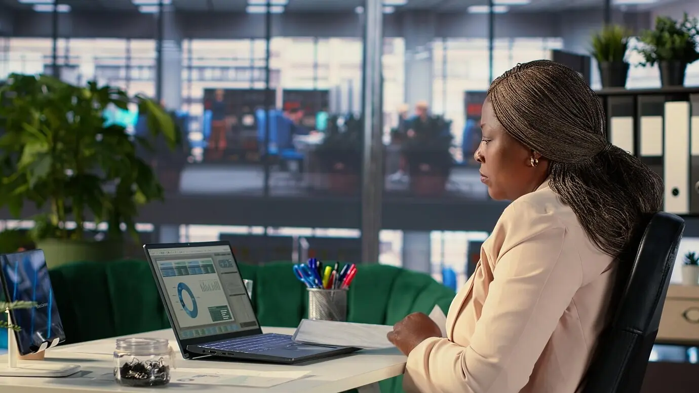 Selbstbewusster afroamerikanischer CEO arbeitet im Firmenbüro mit Datenanalyse.